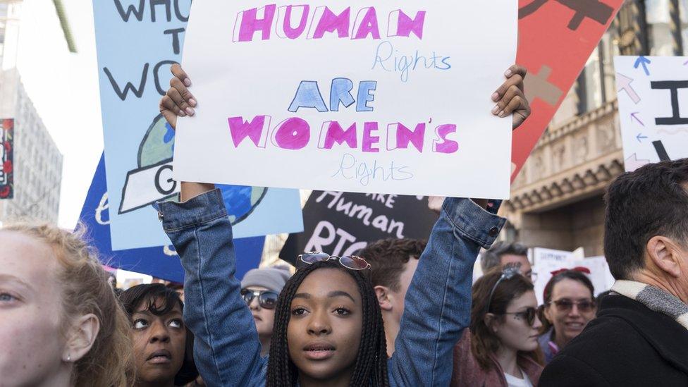 A woman holds a sign in support of women's rights