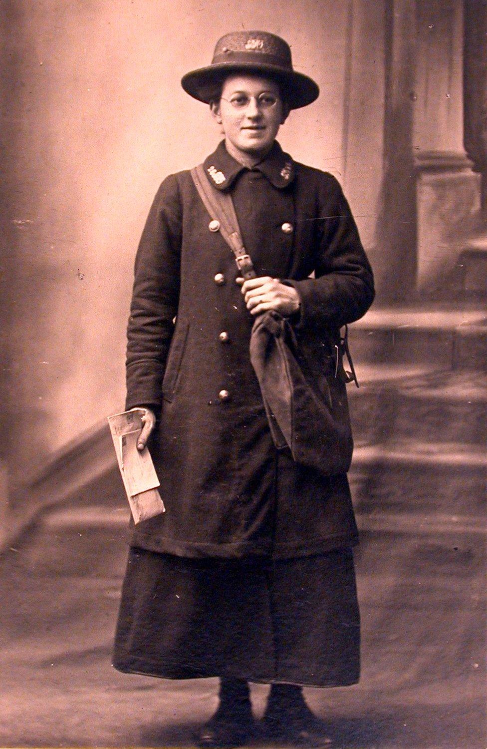 Postcard of a postwoman in her uniform