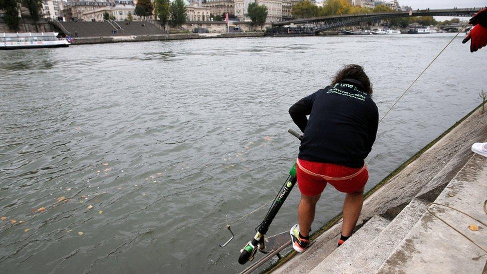 Employees of bicycle-sharing service Lime fish an abandoned electric scooter out of the River Seine in Paris, France