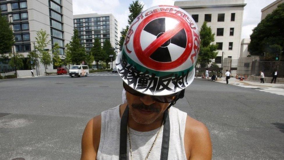 A protester checks a mobile phone during an anti-nuclear rally in front of Prime Minister Shinzo Abe"s official residence in Tokyo, Tuesday, 11 Aug 2015