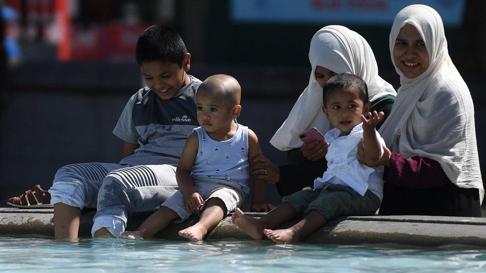 A family take a dip in the fountains of Trafalgar Square in London