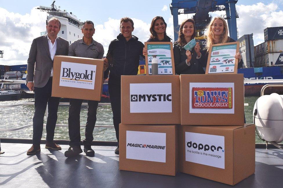 Cargo owners pose in front of a cargo ship powered by vegetable oil