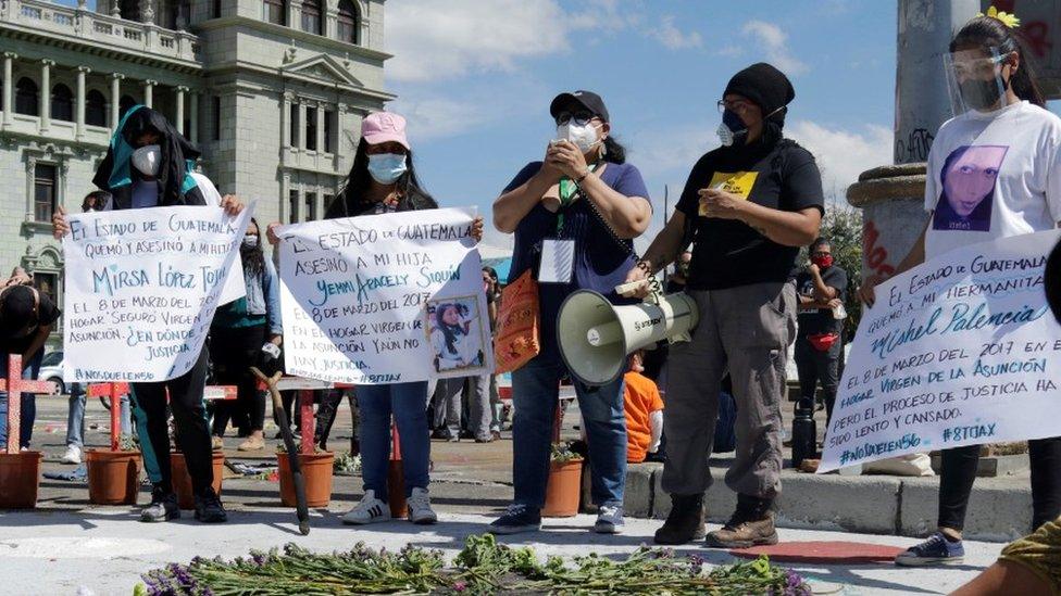 Roxana Tojil and other mothers hold placards during a protest