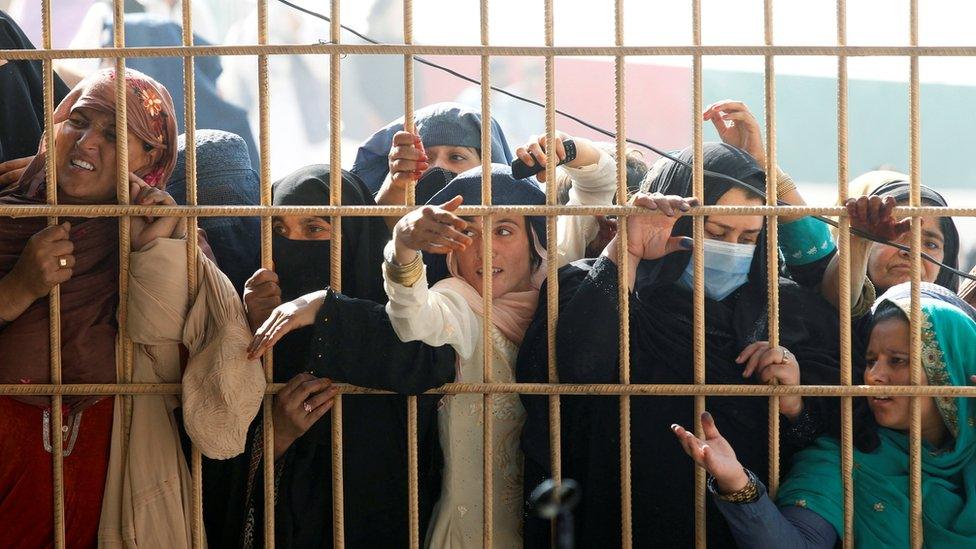 Afghan women wait to receive tokens needed to apply for the Pakistan visa, after some people were killed in a stampede in Jalalabad, Afghanistan October 21, 2020.