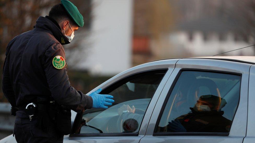 A member of the Guardia di Finanza wearing a face mask stops a car, amid a coronavirus outbreak in northern Italy