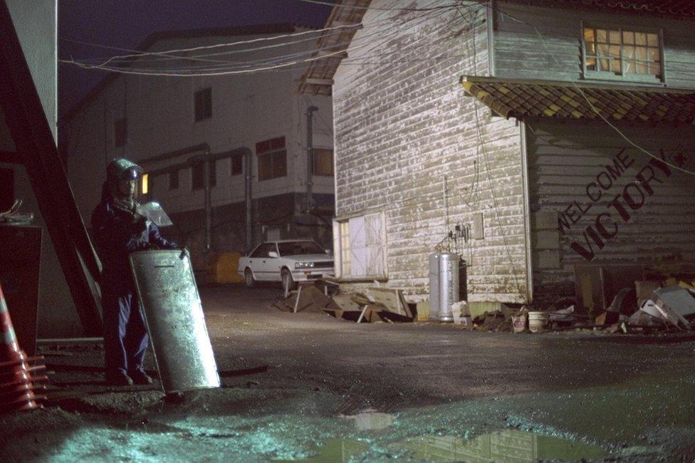 A riot police officer stands guard outside the Aum Shinrikyo cult headquarters 6th compound as the raid continues on 11th May, 1995.