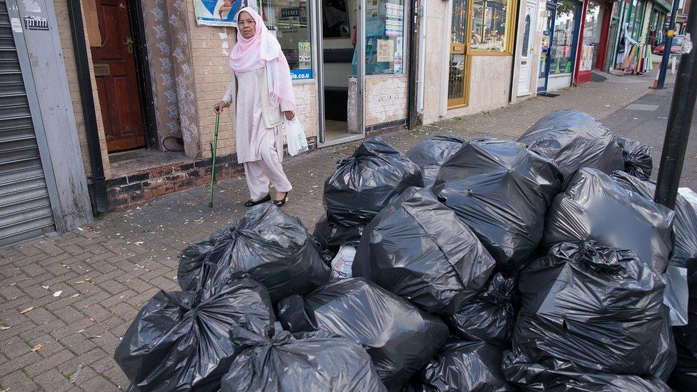 Woman in Alum Rock walks past bin bags