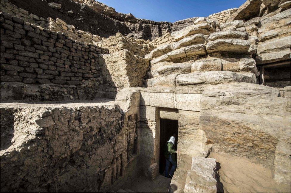 A view of the tomb's exterior, showing its entrance set into rising walls of stone