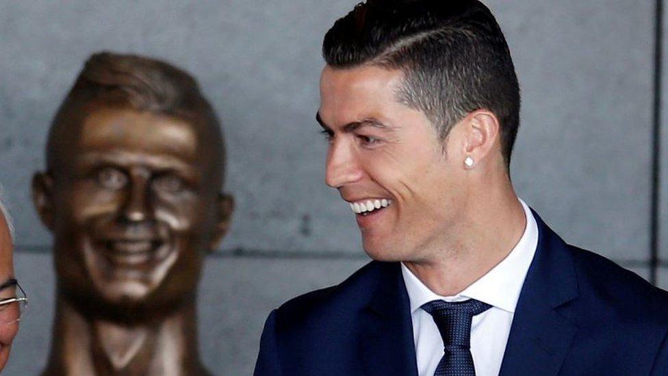 Cristiano Ronaldo stands in front of the statue of himself at Funchal airport,