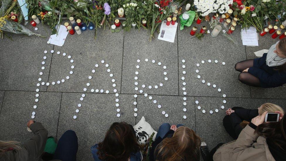 People finish arranging candles into the word 'Paris' next to flowers and messages left at the gate of the French Embassy following the recent terror attacks in Paris on 14 November 2015 in Berlin, Germany.