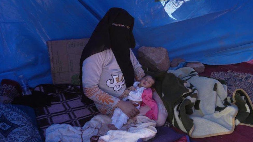 Khadija holding her baby in a tent