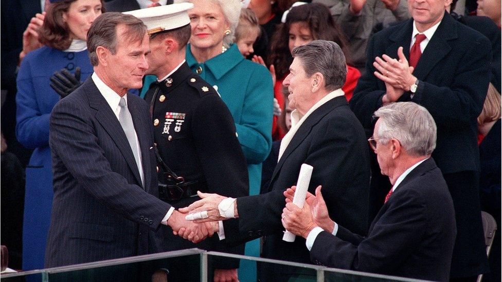 Former US President Ronald Reagan greets newly-inaugurated President George H W Bush as first lady Barbara Bush applauds during Bush's swearing-in ceremony, 20 January 1989, in Washington, DC.