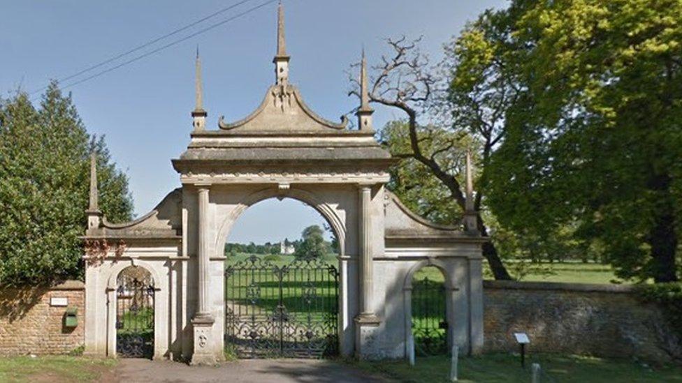 Stone arch surrounding iron gates with trees on either side