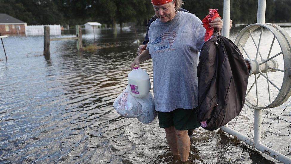 Mary Poche carries items she recovered from her flooded home