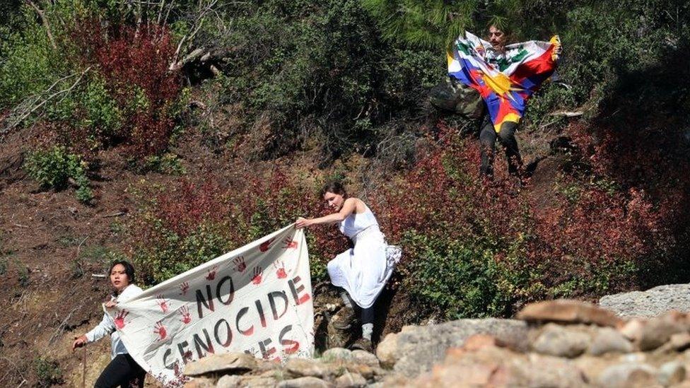 Protesters hold a Tibetan flag and a banner during the Olympic flame lighting ceremony for the Beijing 2022 Winter Olympics