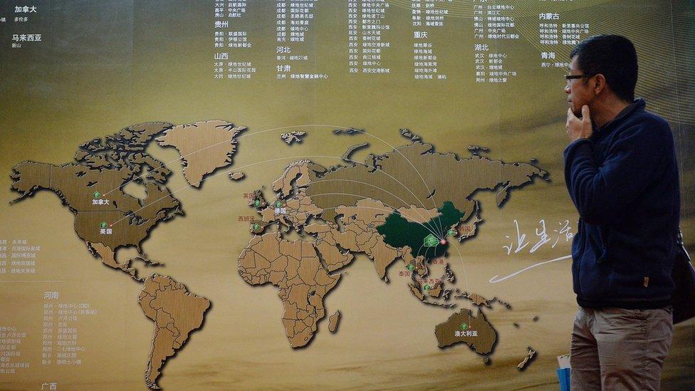 A Chinese investor walks past an investment map showing suitable property markets for wealthy Chinese to invest in at the International Property Expo in Beijing on April 11, 2014.