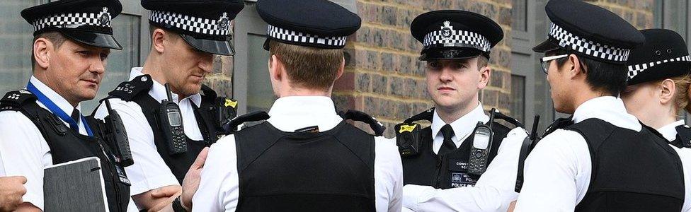 police in uniform stand in a huddle