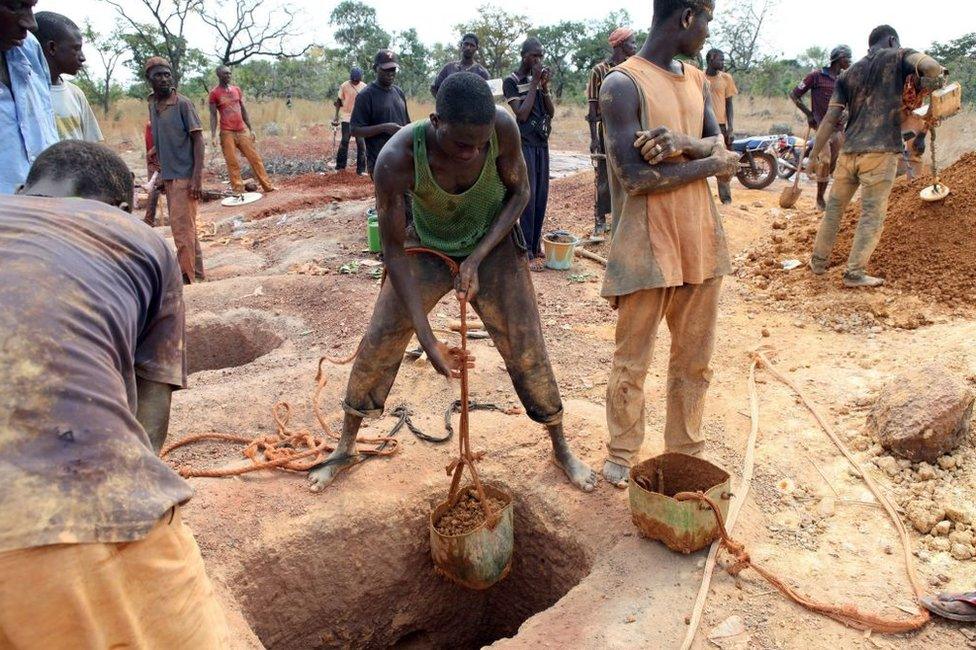 Gold miners empty containers of earth removed from a mining shaft in Koflatie, Mali, on October 28, 2014, a mine located a few miles from the border with its southwestern neighbour Guinea.