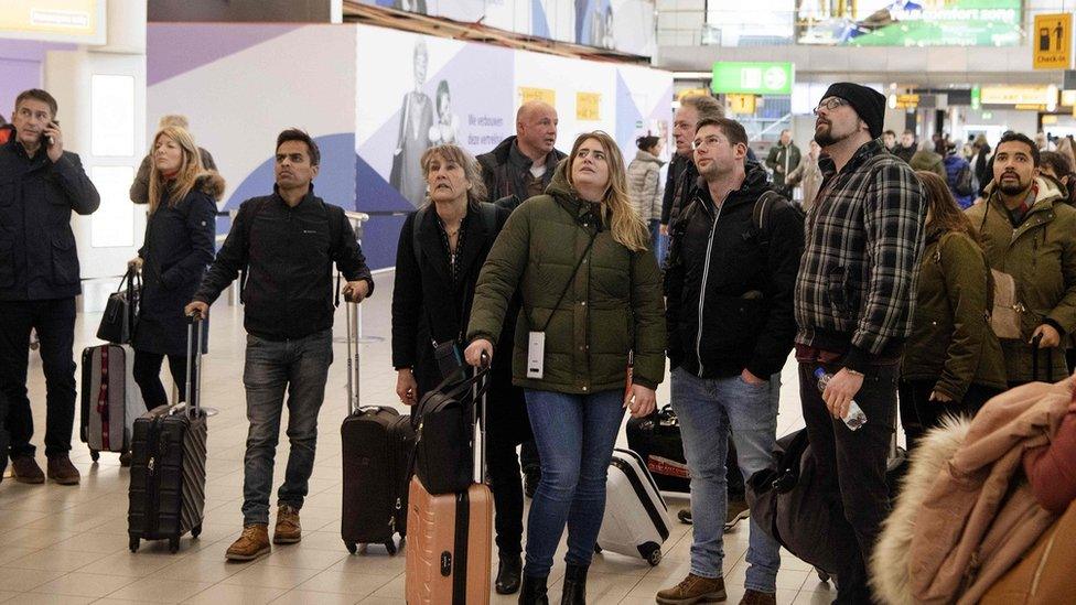 Travellers wait at the departure hall of Schiphol airport