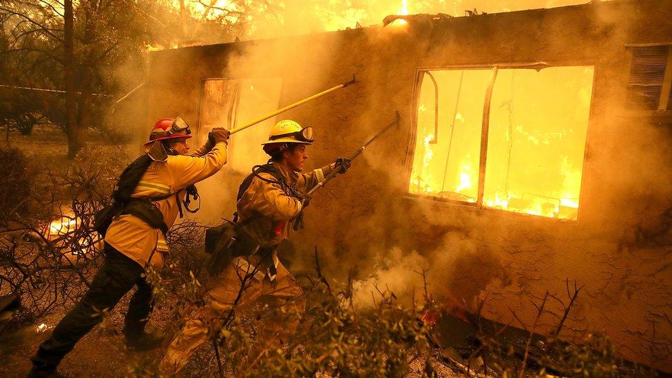 Firefighters try to keep flames from burning home from spreading to a neighbouring apartment complex as they battle the Camp Fire on November 9, 2018 in Paradise, California