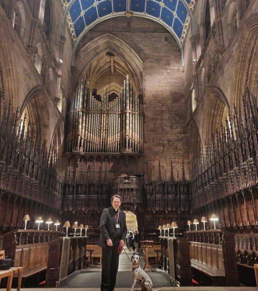 Vicar with Dalmatian in cathedral choir stalls