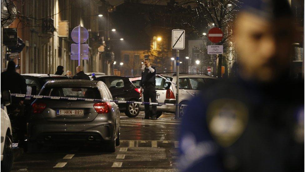 Police guard a check point and man positions during a police raid in the suburb of Schaerbeek in Brussels on 25 March