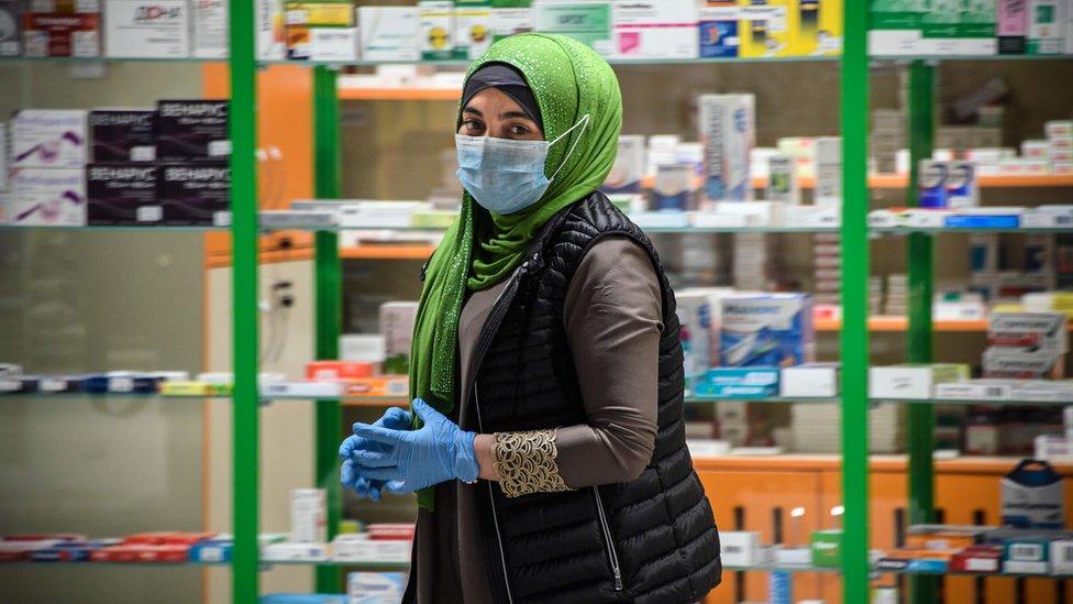 Woman in face mask walks past Moscow pharmacy