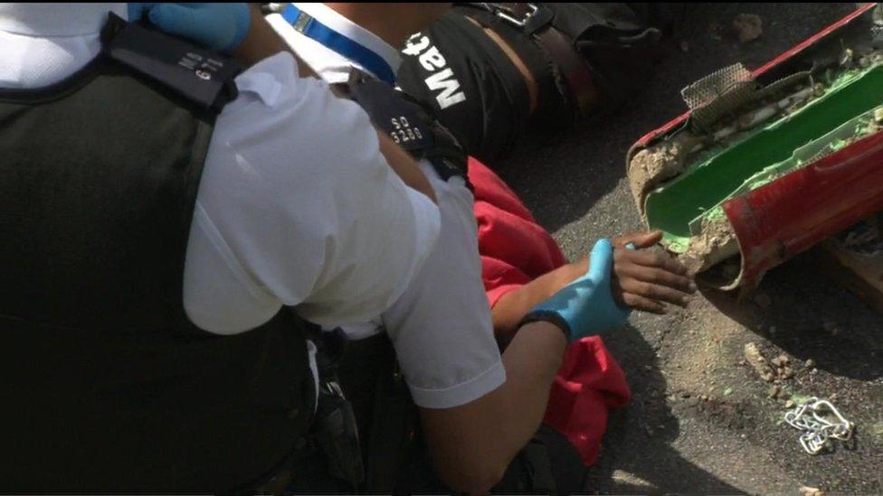 Protesters arm out of a tube