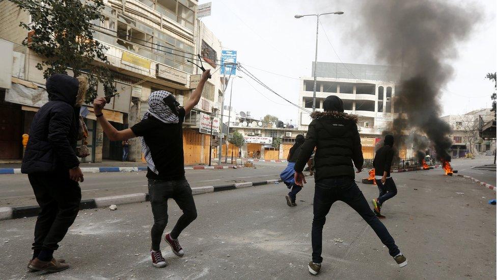 Palestinian protesters throw stones during clashes with Israeli forces in the West Bank city of Hebron, 22 December 2017