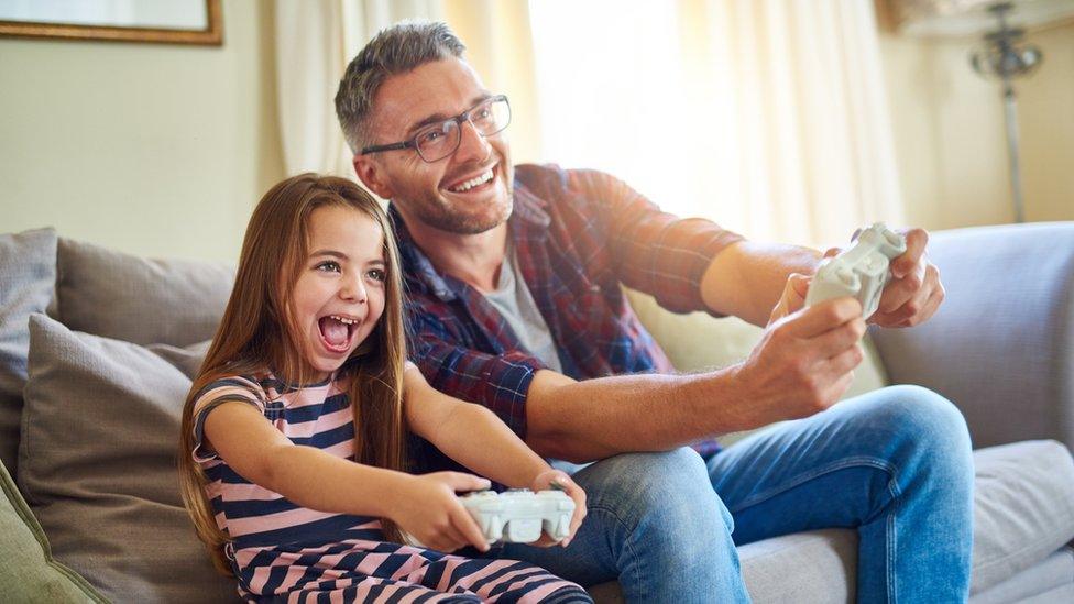 Girl and dad using consoles