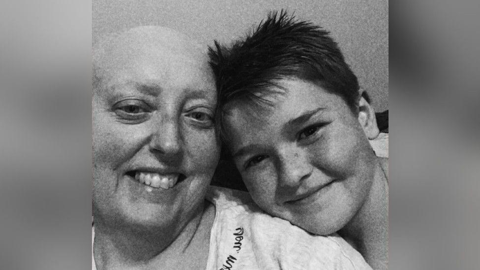 A black and white selfie of Jodie and her son. She is bald and they are leaning their heads together