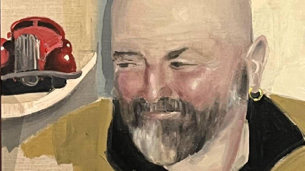 a painting of Hugh, who is bald with a grey beard, wearing one small gold hooped earring and smiling, looking away to the side. In the background of the painting is a red toy car