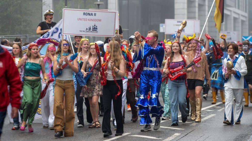 Tall ships crew members in fancy dress on parade through Aberdeen.