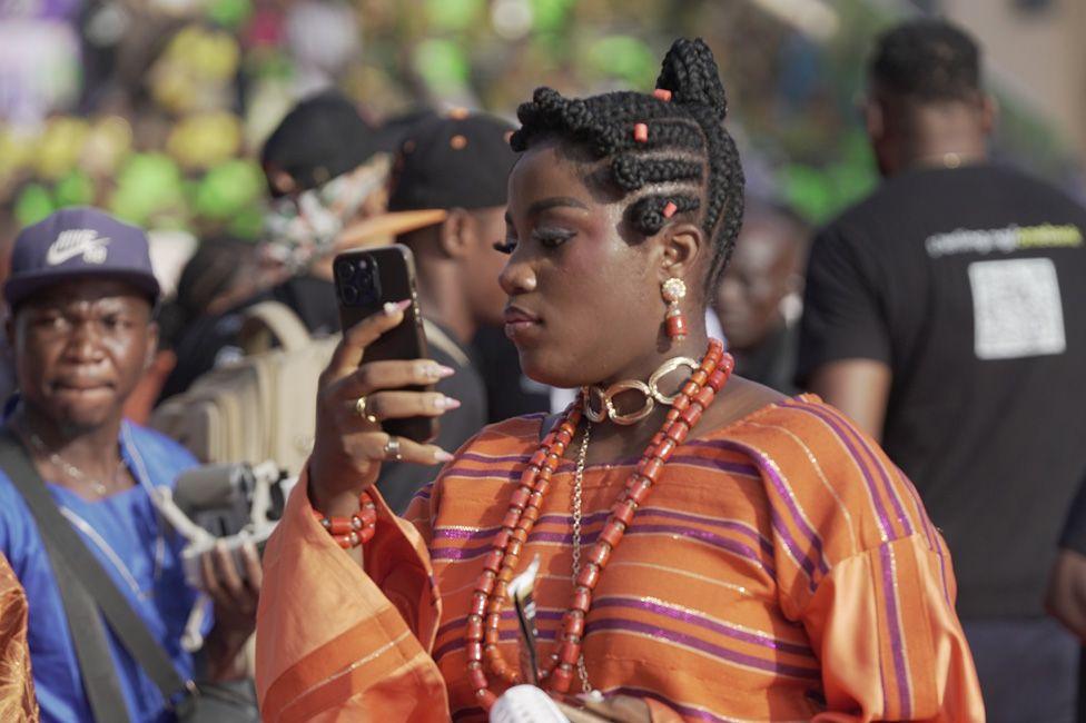 A woman in an orange outfit takes a selfie.