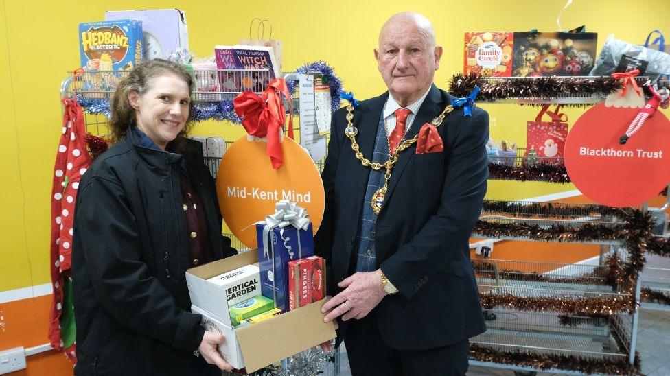 A man and a woman holding a box of goods.