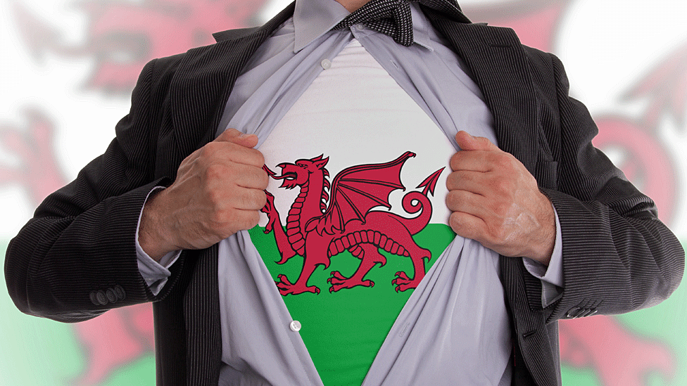 Anonymised man reveals Welsh dragon tee-shirt beneath shirt and jacket in superhero-like pose