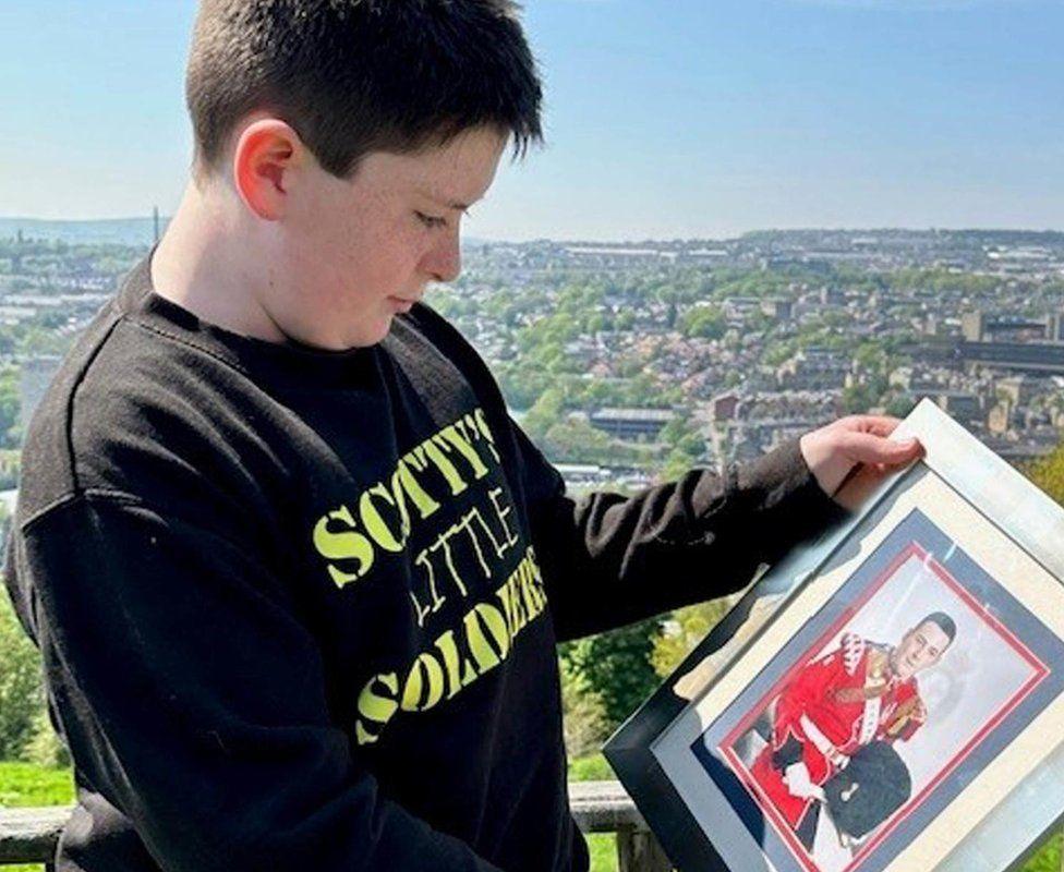 Jack Rigby holding a photo of his father Lee