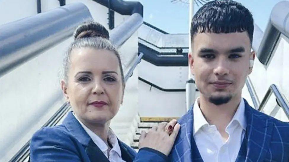 Tatiana (left) and Temur Qureshi (right) stood by some stairs. Her hands are on his shoulders