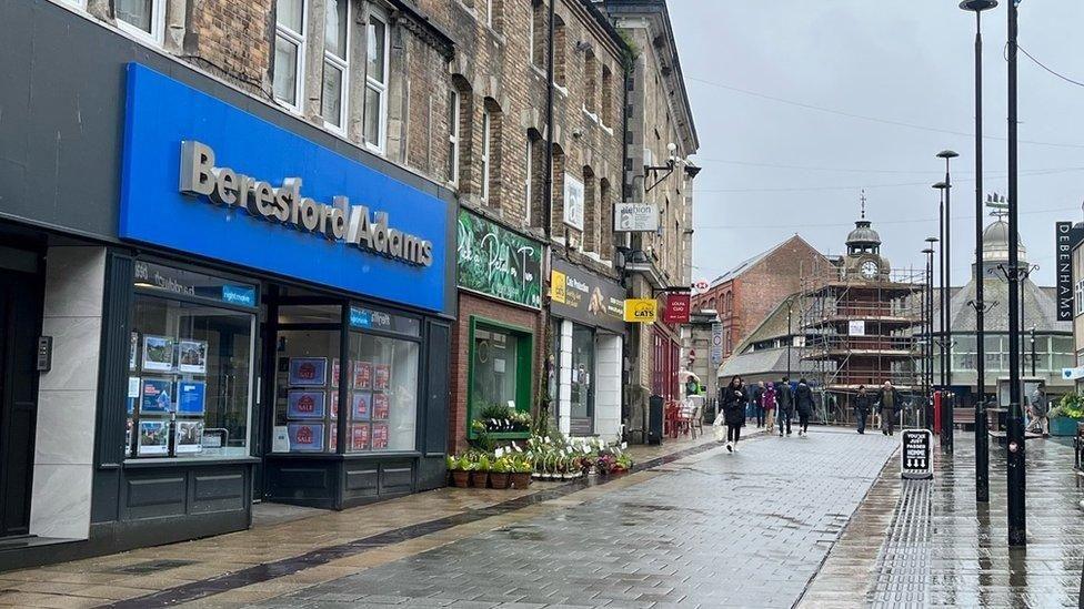 A high street which has a letting agency, bank and charity shops on the street
