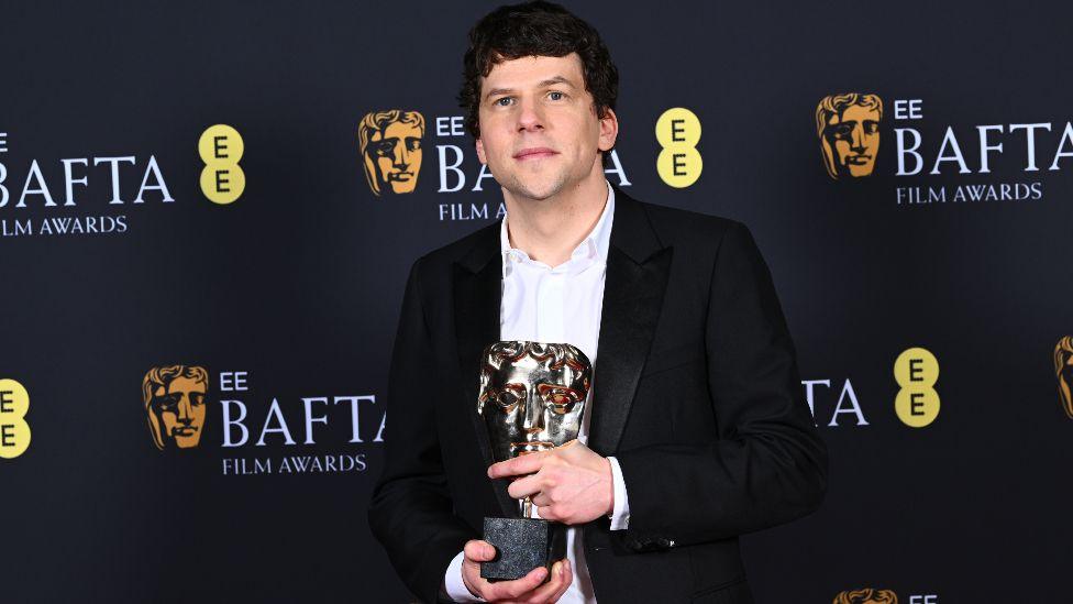 Jesse Eisenberg poses with the Supporting Actor Award, on behalf of Kieran Culkin for 'A Real Pain' in the winners room during the EE BAFTA Film Awards 2025 at The Royal Festival Hall on February 16, 2025 in London, England