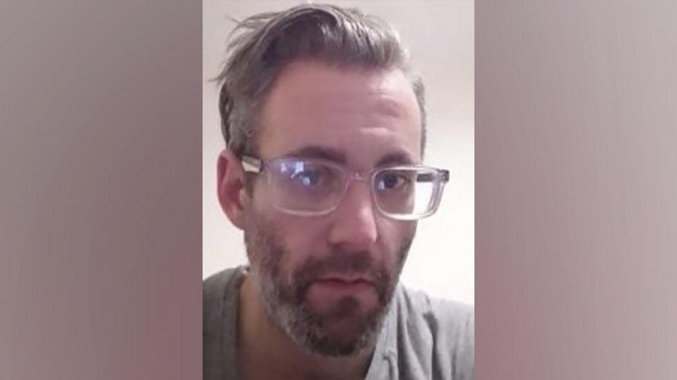 A picture of Michael Wheeler, who has a grey beard, grey T-shirt and glasses