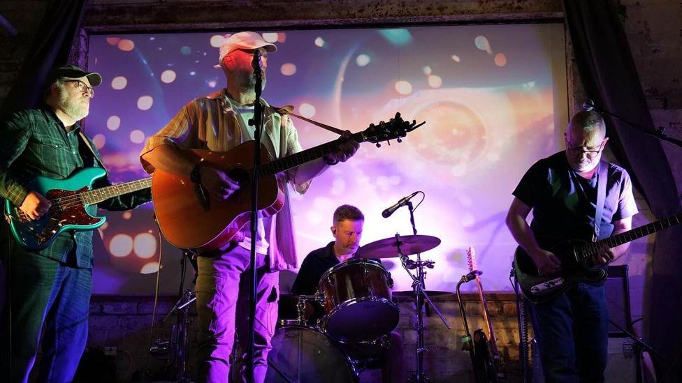 Echoes of The Bunnymen performing on stage bathed in neon light