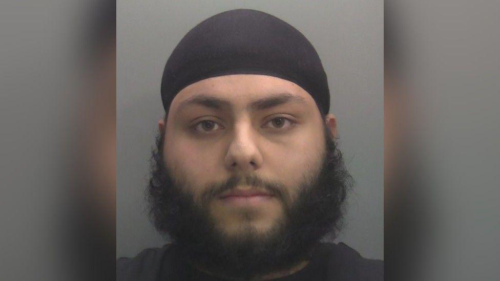 A police custody shot of a bearded man