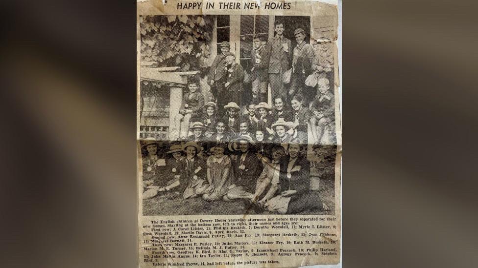 Creased newspaper cutting, headlined "Happy in their New Homes" showing a group of children and listing the following names in a caption: 
Left to right, bottom to top
Bottom row 
J. Carol Litster, 11; Phillipa Hesketh 7; Dorothy Worsdell 11; Myrle I. Litster 9; Ruth Worsdell 13; Martin Davis 8; April Davis 12;
Second row
Anne Rosamund Putley 12; Ann Fry 13; Margaret Hesketh 13; Jean Gibbons 12; Margaret Barnett 14;
Third row
Margaret E. Putley 10; Juliet Masters 11; Eleanor Fry 10; Ruth M. Hesketh 10; Marion M.R. Turner 15; Belinda M.J. Putley 14:
 Fourth row
Geoffrey K. Bird 9; Alan G. Taylor 9; Ian Michael Peacock 10; Philip Harland 13; John Martin Angus 14; Ian Taylor 11; Roger S. Bennett 9; Antony Peacock 9; Stephen Bird 9.
The caption says Valerie Winifred Payne 14, had left before the picture was taken.
