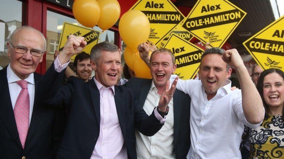 Menzies Campbell with Lib Dem colleagues Willie Rennie, Tim Farron and Alex Cole-Hamilton.  They are campaigning with balloons and Lib Dem posters.  