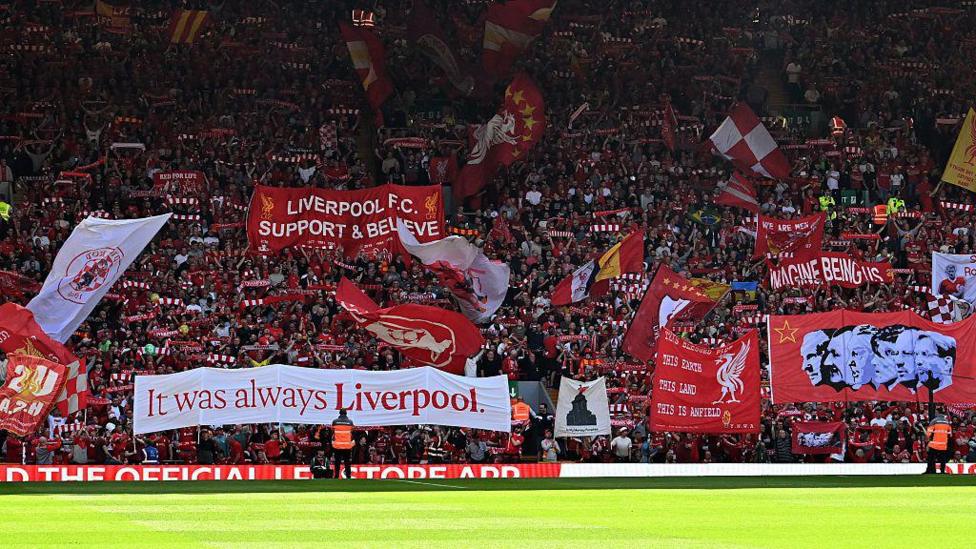The crowd hold up banners and flags inside the stadium