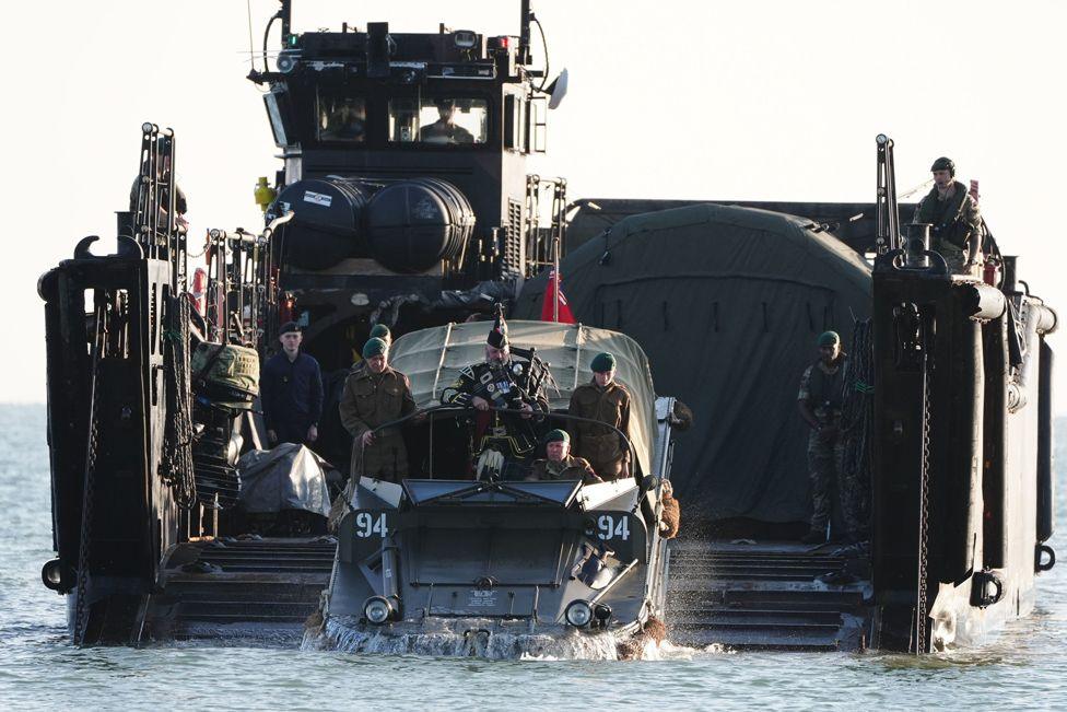 A military piper comes into shore on a DUKW amphibious vehicle ahead of playing a dawn lament on Gold Beach in Arromanches in Normandy, France, June 6, 2024.