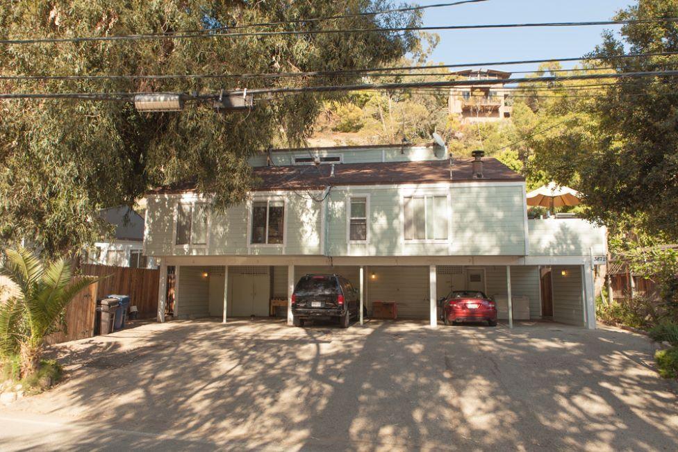 A multi-unit property with cars parked underneath it