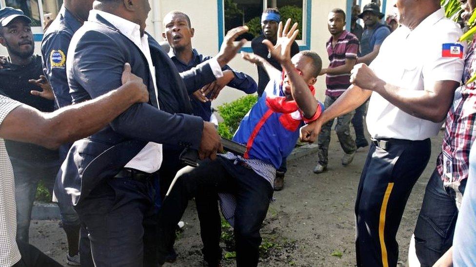 Haitian Senator Willot Joseph holds a gun as he pushes an opposition supporter in Port-au-Prince, Haiti