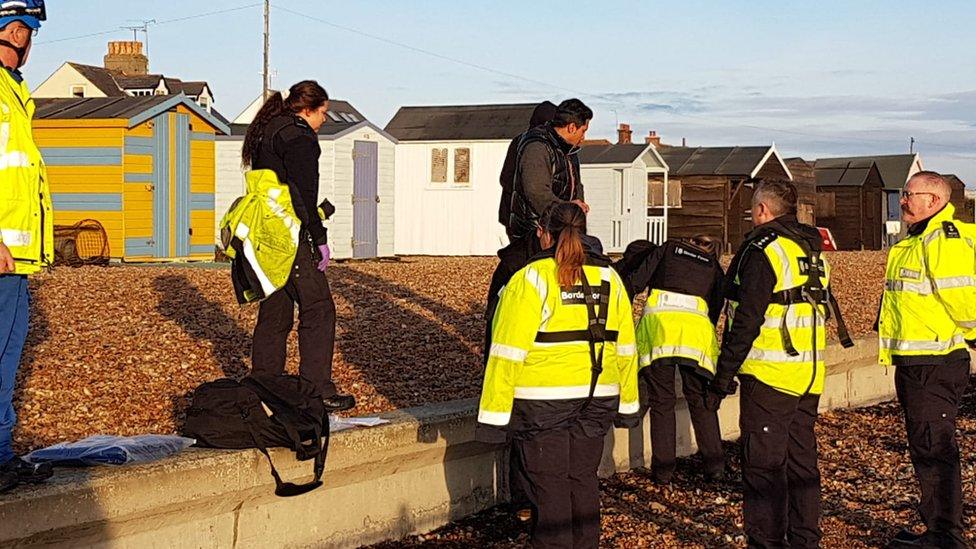 Men on the beach with Border Force officers